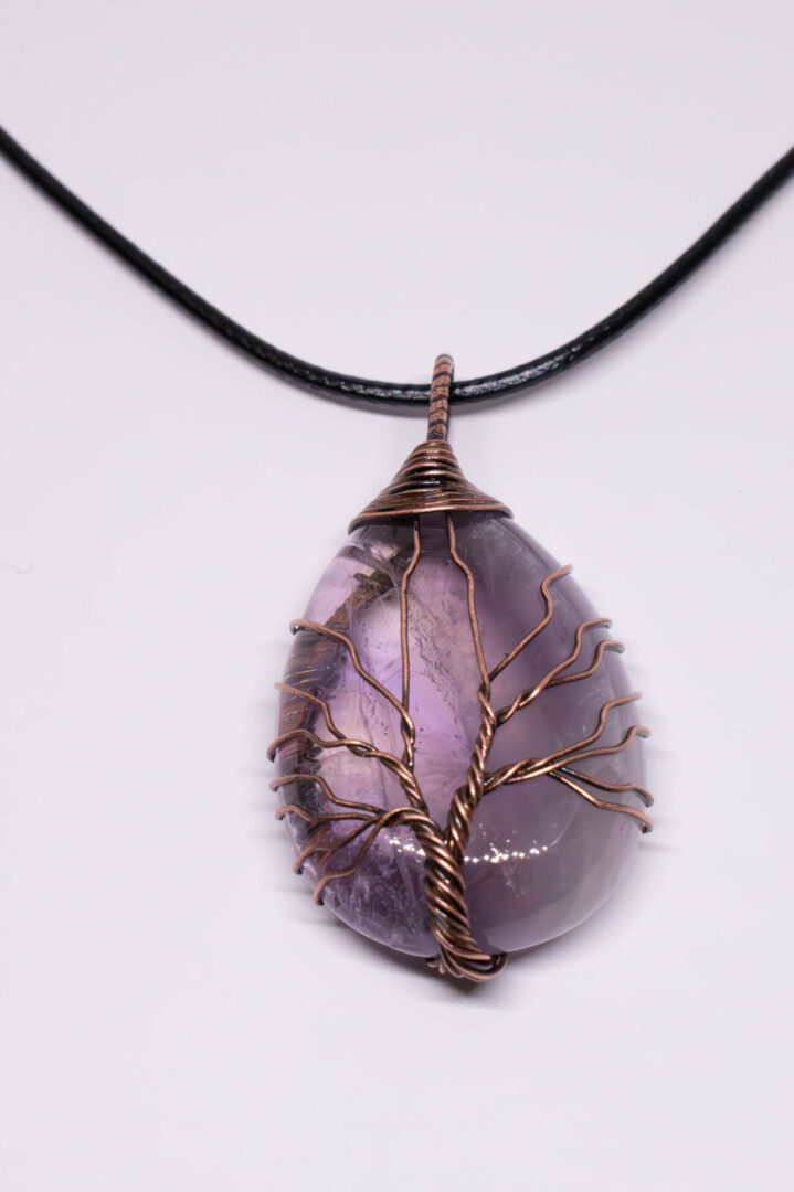 A necklace with an amethyst stone and wire tree of life.