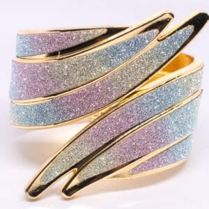 A gold bracelet with two different colors of glittery material.