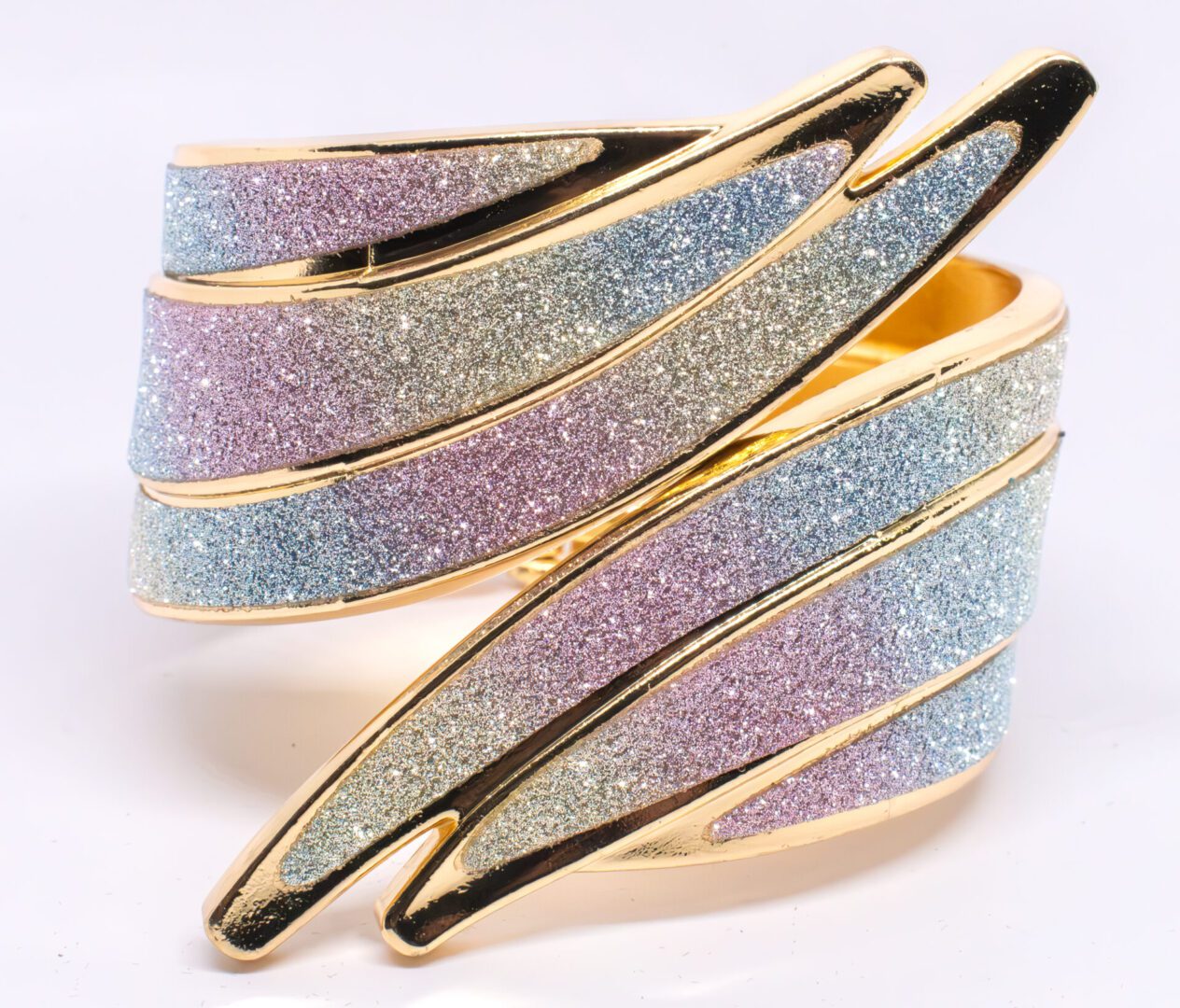 A gold bracelet with two different colors of glittery material.